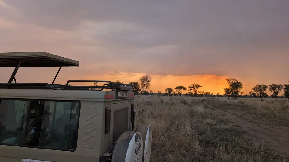 Safari vehicle on the Serengeti plains at sunset